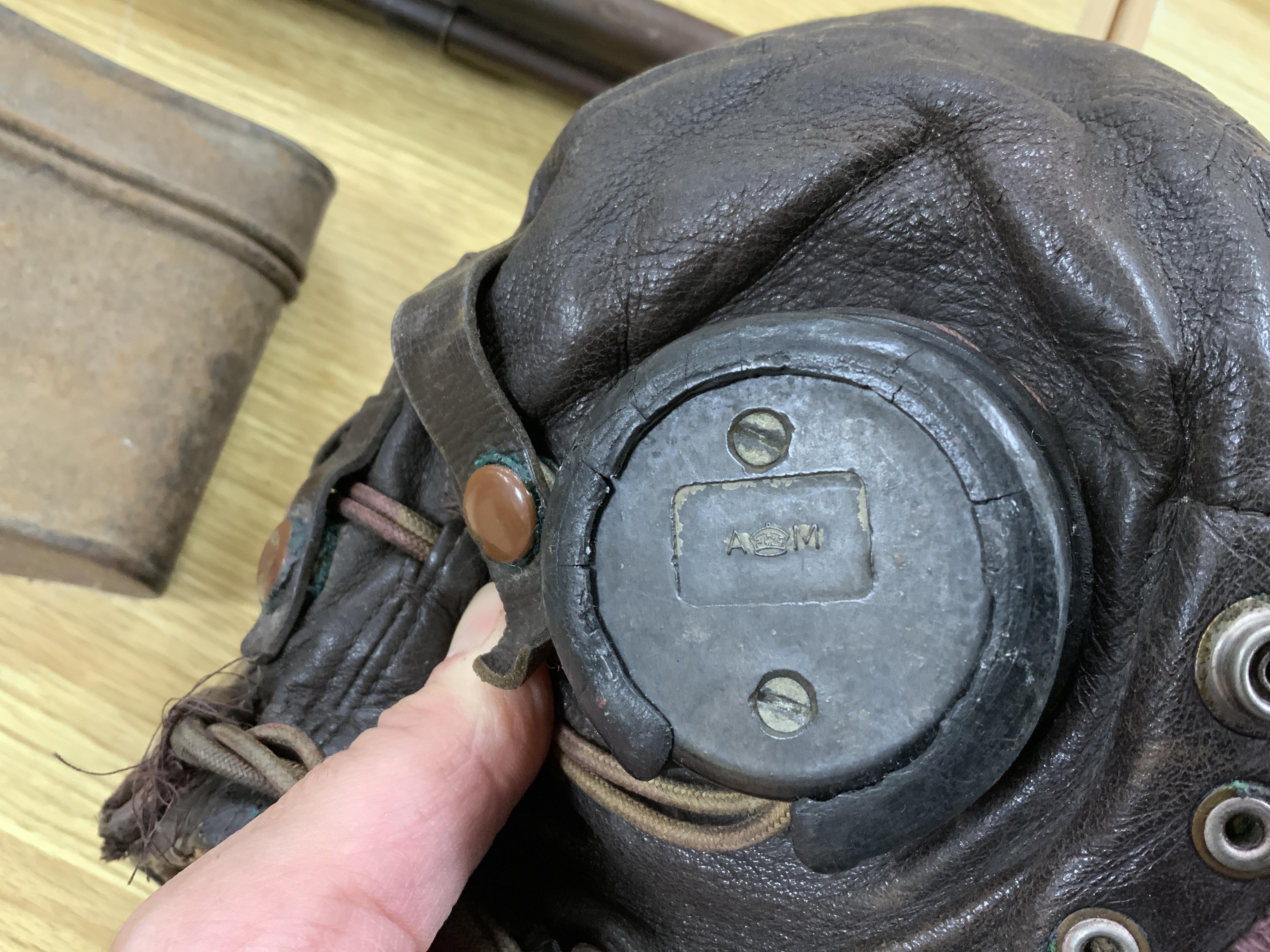 A WWII RAF Air Ministry aviator’s leather head-gear, with built-in padded headphones, oxygen mask with microphone and other electrics incorporated into it, marked with a crown and ‘AM 10A/13466’ to one earpiece, together